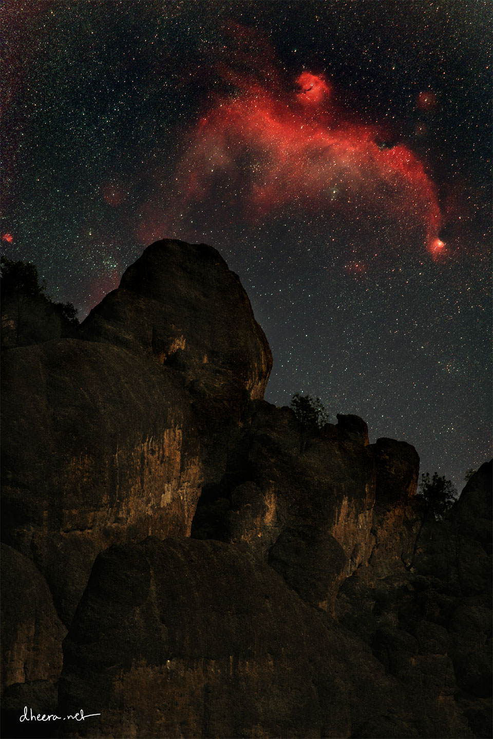 A red nebula in a dark starry sky is seen above a rocky
peak. The nebula appears similar to a flying bird.
Please see the explanation for more detailed information.