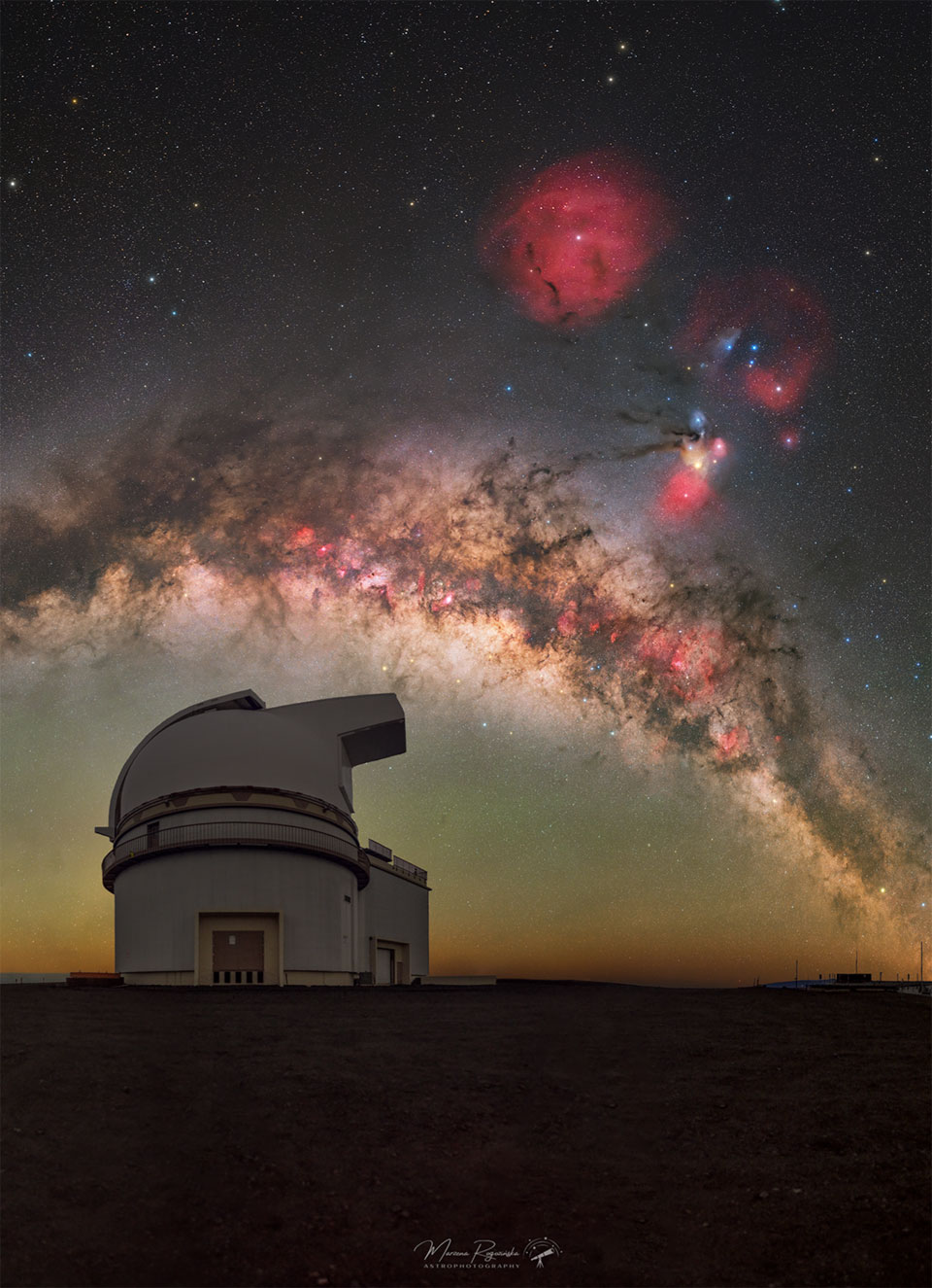 A wide starfield is shown with the dark and light
band arching horizontally across the middle. On the right
is a colorful and complex nebula, and near the top 
center is a red circular nebula.
Please see the explanation for more detailed information.