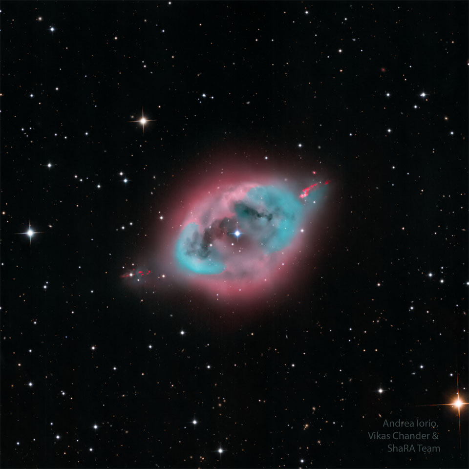 A dark starfield highlights a blue and pink nebula
in its center. Some dark lanes of dust are seen inside
nebula's center. 
Please see the explanation for more detailed information.