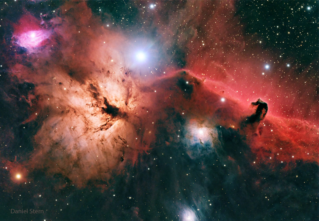 A starfield is shown with bright and dark nebulae of 
different shapes and colors.
Please see the explanation for more detailed information.