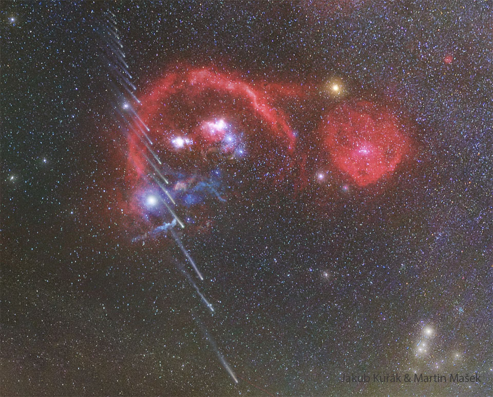 A starfield shows many red nebulas near the center. 
Running vertically up the left side are about 20 images of a
comet, with the head towards the image bottom.  Successively
higher images of the comet show successively shorter
tails. 
Please see the explanation for more detailed information.